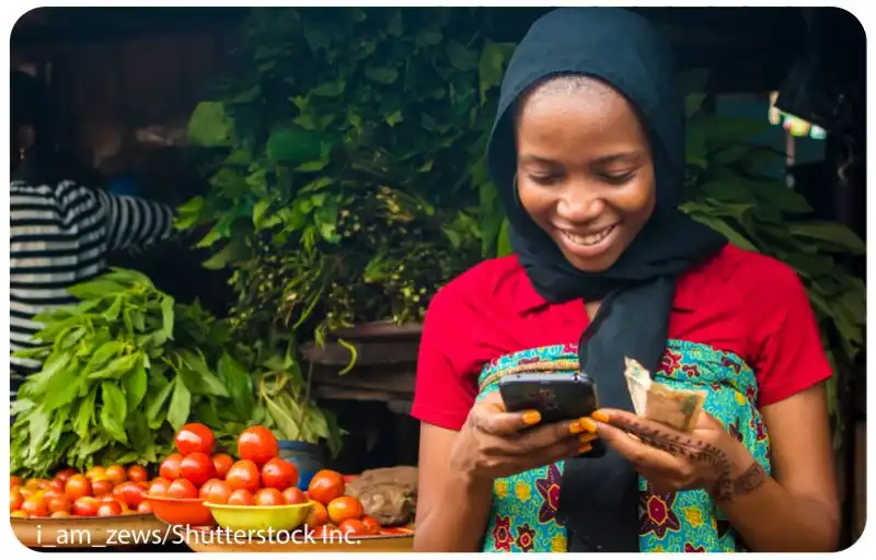 Lady using a mobile phone to pay at a vegetable market